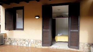 Une chambre avec un lit, une armoire et un petit balcon doté d’un mur en pierre et d’un sol carrelé.