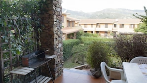 Une terrasse avec un mur en pierre, un barbecue et une table avec des chaises.