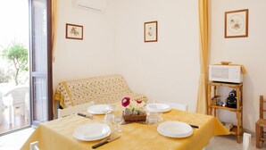 Un coin repas avec une nappe jaune, des assiettes blanches et un panier de fleurs.