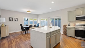 A modern kitchen with a large island, built-in appliances, and a dining area with a view. - Experience the heart of downtown, where historic charm meets modern comforts. (Huntsville)