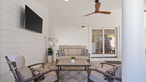 A patio area with a sofa, chairs, a coffee table, and a ceiling fan. - Experience the heart of downtown, where historic charm meets modern comforts. (Huntsville)
