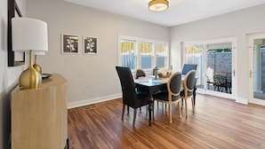 A dining area with a wooden table, black chairs, and a gold lamp. - Experience the heart of downtown, where historic charm meets modern comforts. (Huntsville)