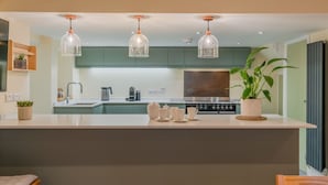 A modern kitchen with a central island, pendant lights, and a stove. - The Weir House - Symonds Yat (Symonds Yat)