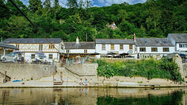 A riverside building with a stone staircase leading to a dock, surrounded by lush greenery. - The Weir House - Symonds Yat (Symonds Yat)