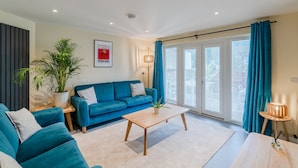 A modern living room with a blue sofa, a wooden coffee table, and a potted plant. - The Weir House - Symonds Yat (Symonds Yat)