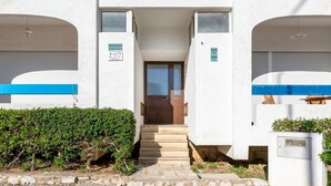 Ein Gebäude mit einem zentralen Eingang, zwei Balkonen und einer blauen Markise.