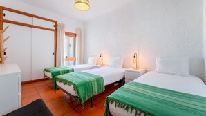 Ein Hotelzimmer mit zwei Betten, einem Schreibtisch und einem Kleiderschrank.