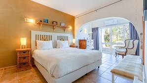 A hotel room with a large bed, a nightstand, a dresser, a chair, and a balcony with a view. - Cozy 2 BDR W/Balcony in Vale do Lobo by LovelyStay (Almansil)