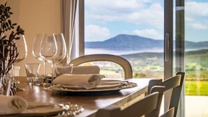 A dining table with a view of a mountainous landscape through a large window. - Pittulongu Olbia Residence A Domo Mea Retreat (Pittulongu)