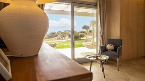 A room with a wooden table, a lamp, a chair, and a view of the outdoors through a glass door. - Pittulongu Olbia Residence A Domo Mea Retreat (Pittulongu)