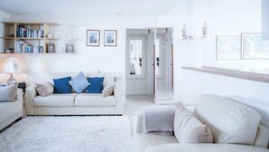 Ein modernes Wohnzimmer mit einem weißen Sofa, einem Bücherregal und gerahmten Bildern an der Wand.