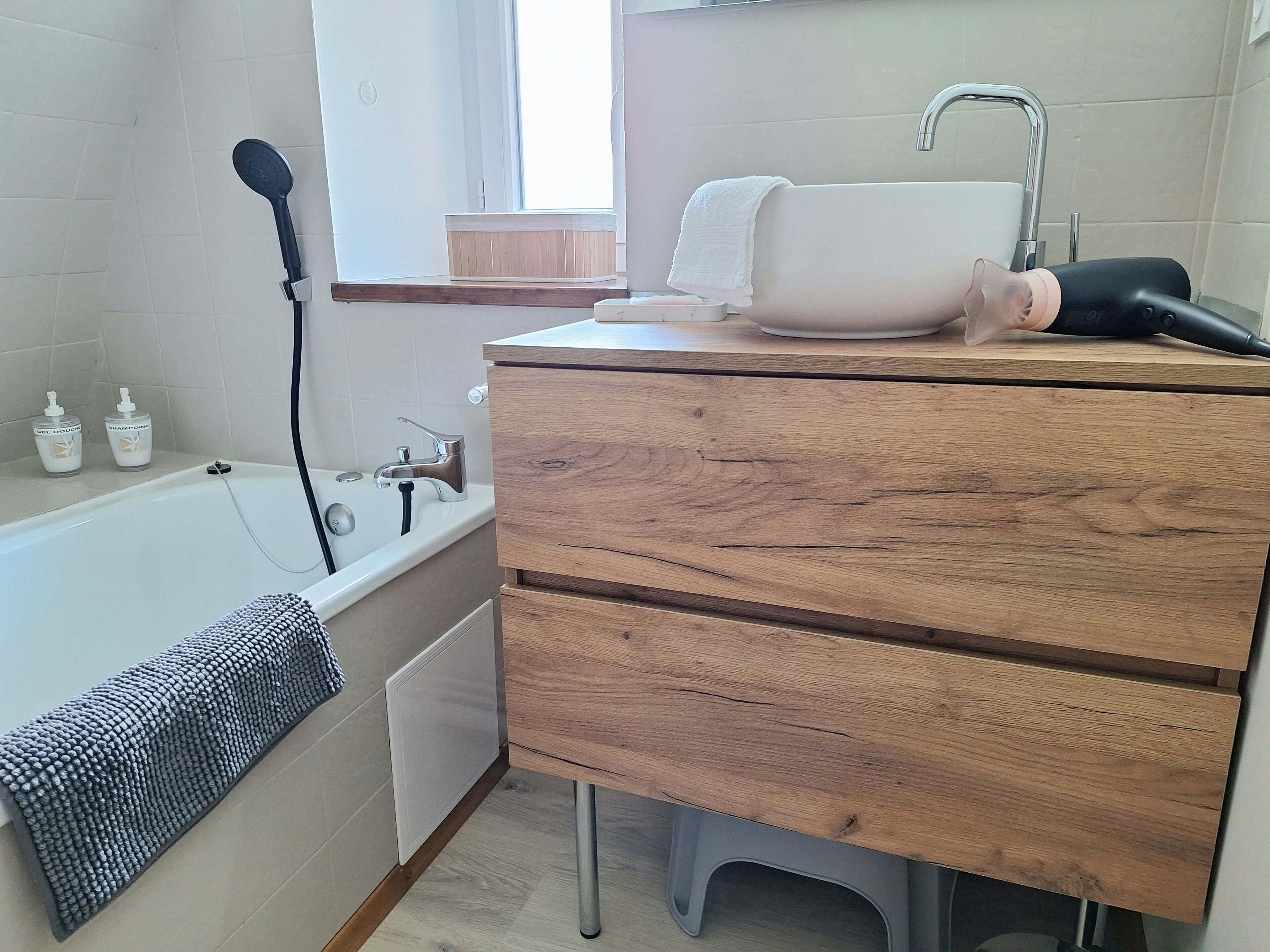 Un baño con tocador de madera, bañera, cabezal de ducha y perchero.