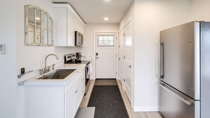 A modern kitchen with white cabinetry, a stainless steel refrigerator, and a microwave. - Port Orchard Guest House - Walk to Bay Street! (Port Orchard)