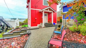 A red house with a front porch, steps leading to the door, and a garden area with a pathway and chairs. - Port Orchard Guest House - Walk to Bay Street! (Port Orchard)