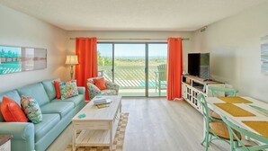 Een woonkamer met een bank, salontafel, televisie en een balkon met uitzicht.