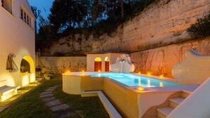 Ein Schwimmbecken mit einer gefliesten Terrasse, einem Steinweg und einer Treppe, die zu einem Gebäude führt.
