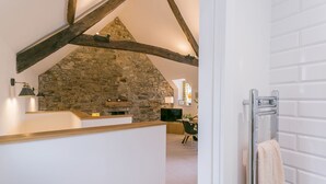 Una pared de piedra rústica con vigas de madera en el techo, una encimera de madera y un baño moderno con un perchero para toallas.
