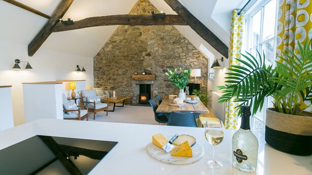 Un interior acogedor con chimenea de piedra, vigas de madera y un comedor con mesa puesta para una comida.