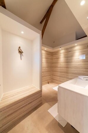 Une salle de bain moderne avec une baignoire sur pieds, un panneau mural en bois et un meuble-lavabo blanc.