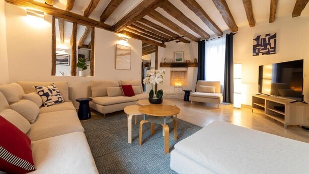 Een moderne woonkamer met een grote hoekbank, een kleine ronde tafel en een televisie.