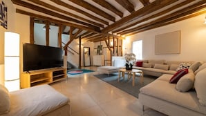 Een ruime woonkamer met een grote flatscreen-tv, een bank, een salontafel en een eethoek.