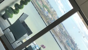A modern office space with a large window offering a view of a cityscape. There is a yellow chair and a white table in the foreground. - Stunning 1-bed Apartment in London With River View (London)