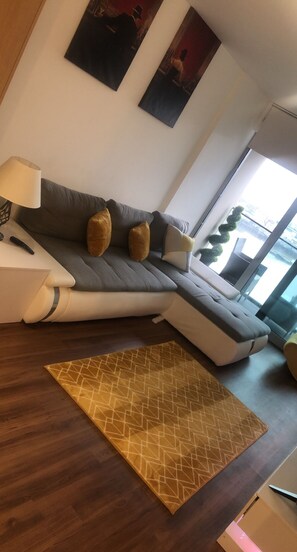 A modern living room with a sectional sofa, a patterned rug, and artwork on the walls.