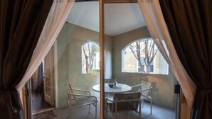Una habitación con puerta de vidrio, una mesa redonda con sillas y dos ventanas de arco.