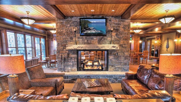 A stone fireplace with a TV above it, leather sofas, and a chessboard on a wooden table. - Old Greenwood Cabin 14 (Truckee)