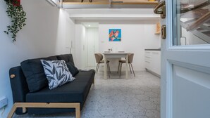 A compact living space with a sofa, a dining table, and a staircase leading to an upper level. - Studio Sineo by Wonderful Italy (Turin)
