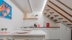 A modern kitchen with white cabinets, a wooden staircase, and a colorful painting on the wall. - Studio Sineo by Wonderful Italy (Turin)