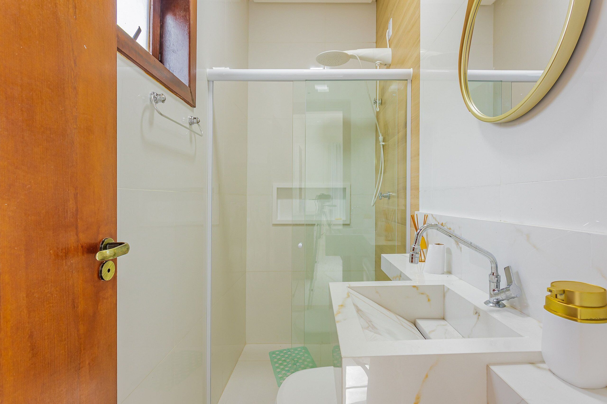 Un bagno con doccia vetrata, lavabo con contenitore dorato e specchio a parete.