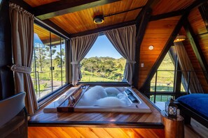 A wooden cabin with a large bathtub, curtains, and a view of the landscape. - Sítio Mar de Nuvens Chalés de Luxo (Urubici)