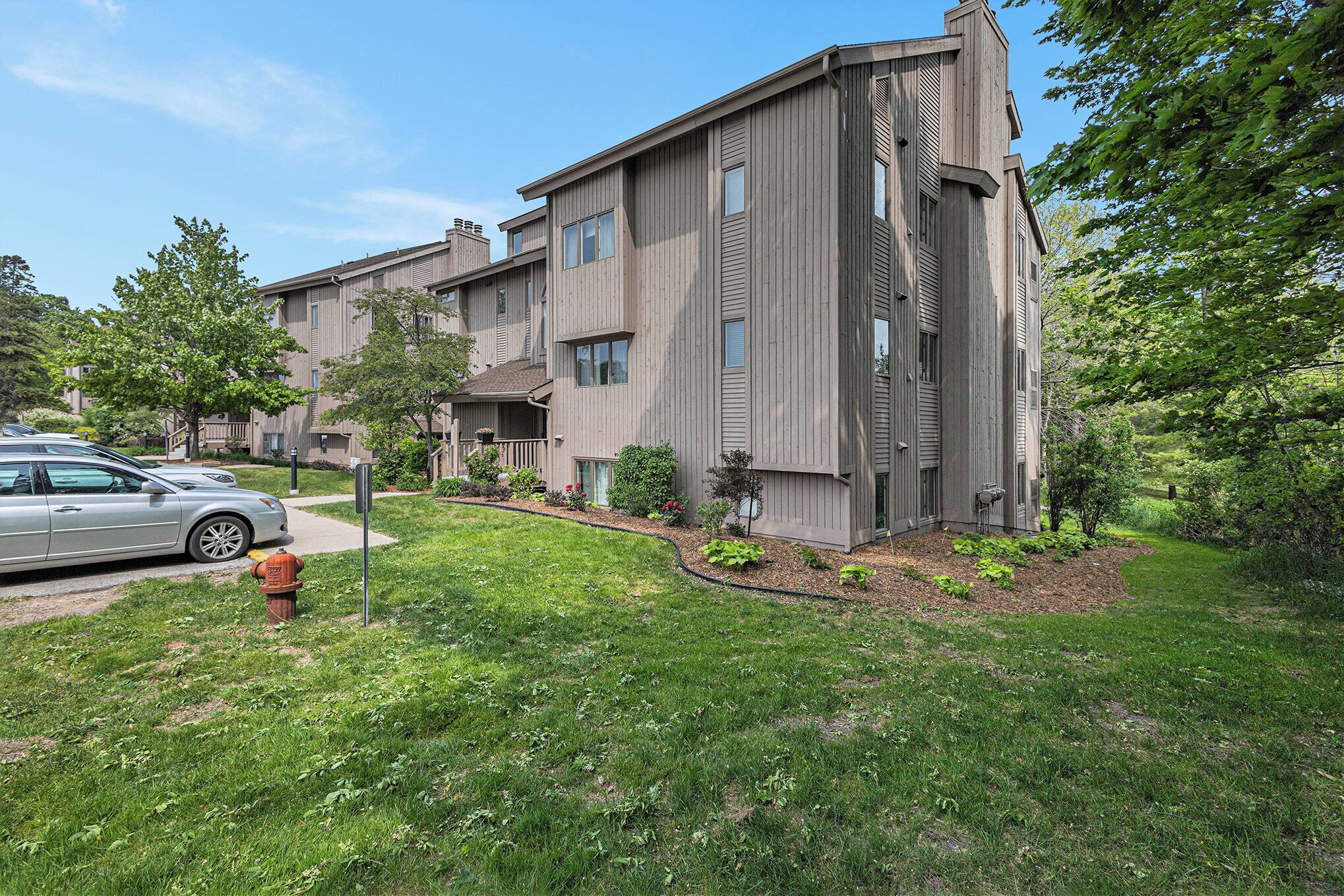 A multi-story residential building with a modern design, featuring a well-maintained lawn and a fire hydrant in the foreground.