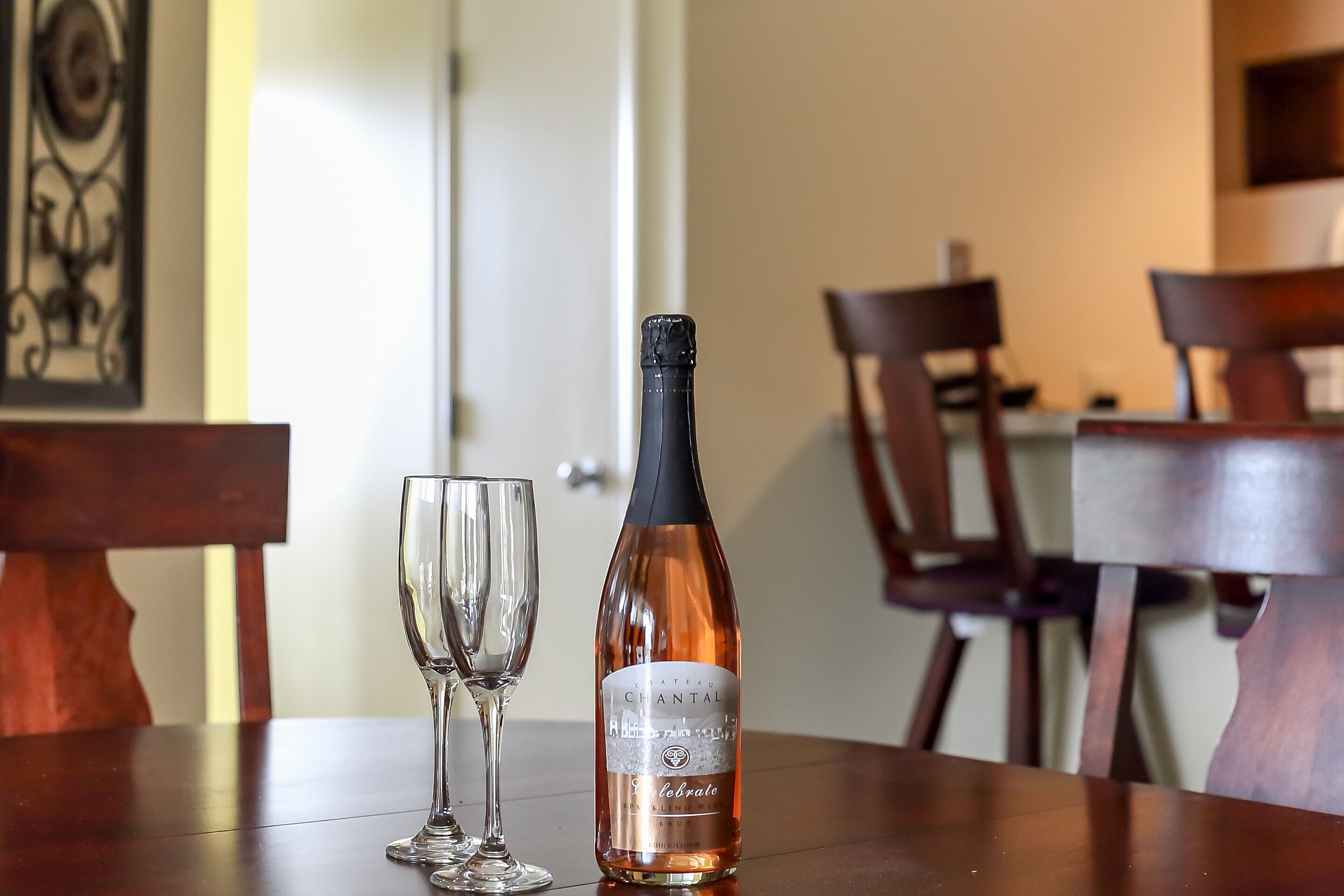 Una botella de Chateau Montant sobre una mesa de madera con una copa al lado.