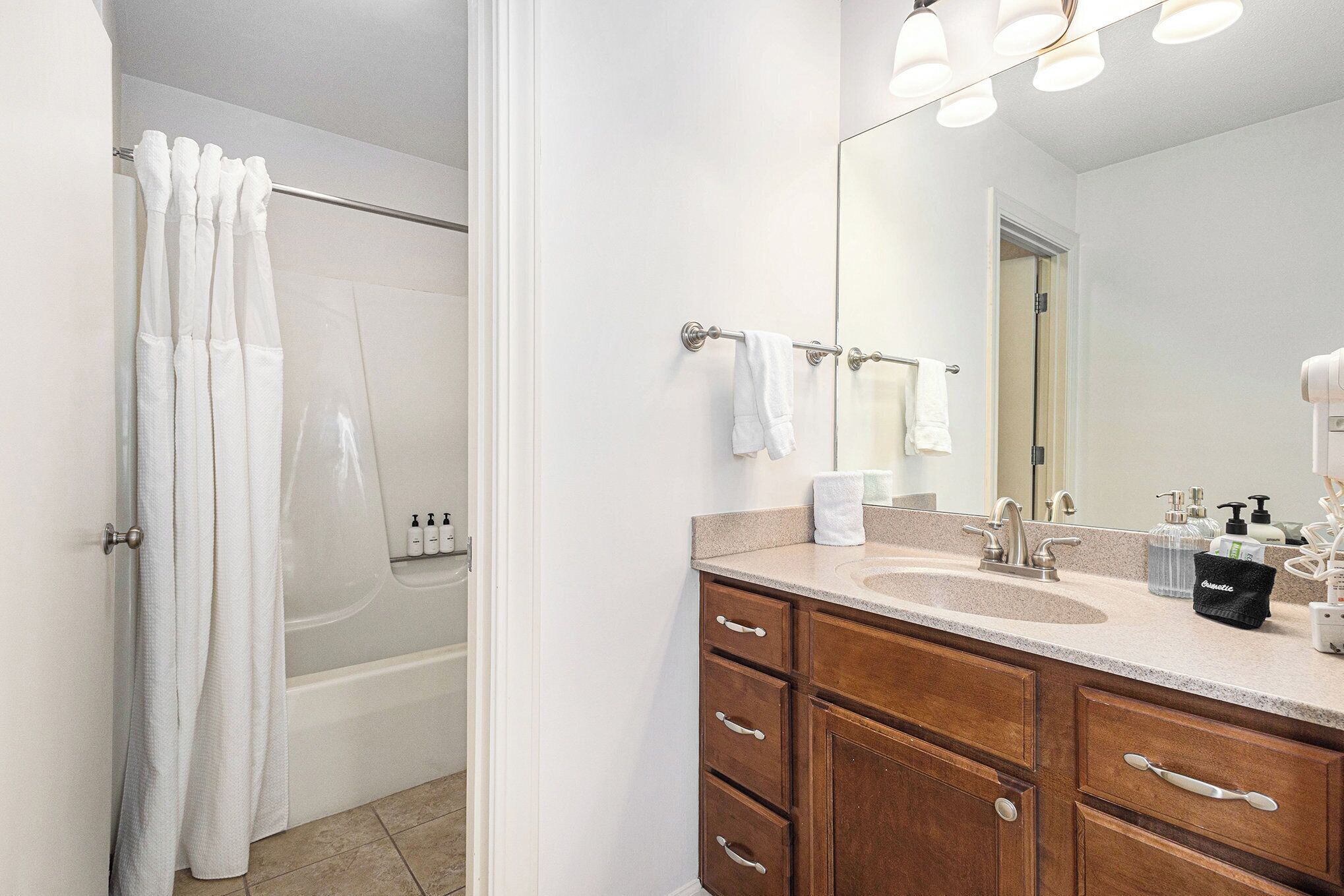 Une salle de bain avec une baignoire, un lavabo avec un miroir et des meubles en bois.