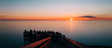 A pier extending into calm water during sunset.