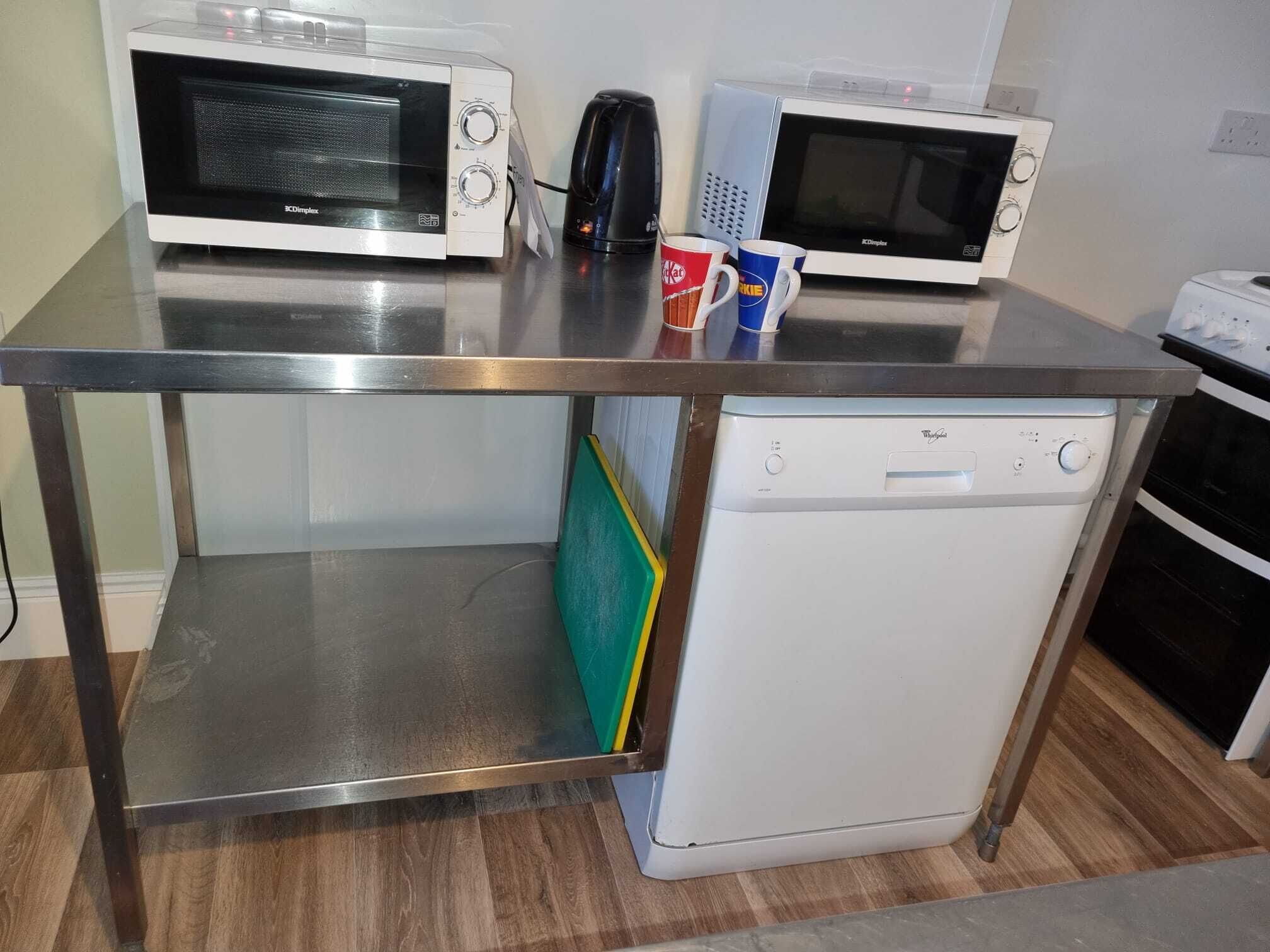 Una cocina equipada con dos microondas, una cafetera y un lavavajillas.