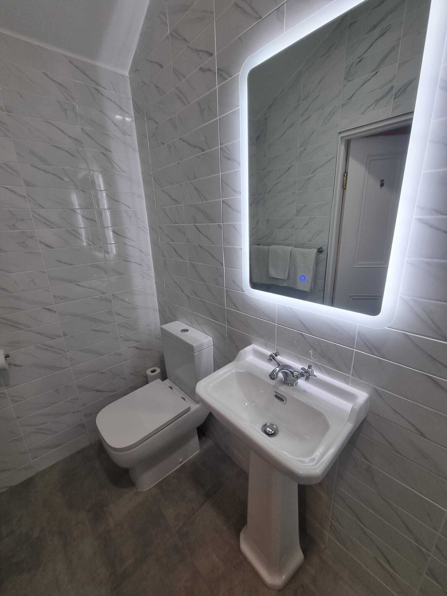 Une salle de bain avec des toilettes, un bidet et un lavabo, le tout de couleur blanche.