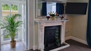 A room with a fireplace, a large mirror, and a television mounted on the wall. - The Monkey Puzzle (Bunclody)