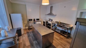 A modern kitchen with a central island, stainless steel appliances, and a hanging light fixture. - The Monkey Puzzle (Bunclody)