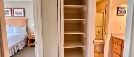 A bedroom with a bed, a nightstand, and a closet with shelves.