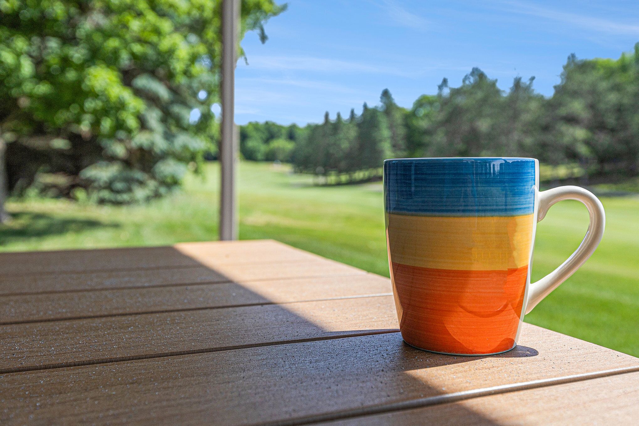 A wooden table with a colorful mug on it.