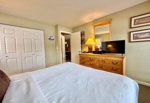 Una habitación de hotel con cama, cómoda, televisor y espejo.