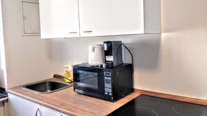 A compact kitchen with a microwave, coffee maker, and a sink. - Mainhouse  (Düsseldorf)
