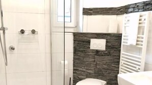 A modern bathroom with a shower, toilet, and sink. - Mainhouse  (Düsseldorf)
