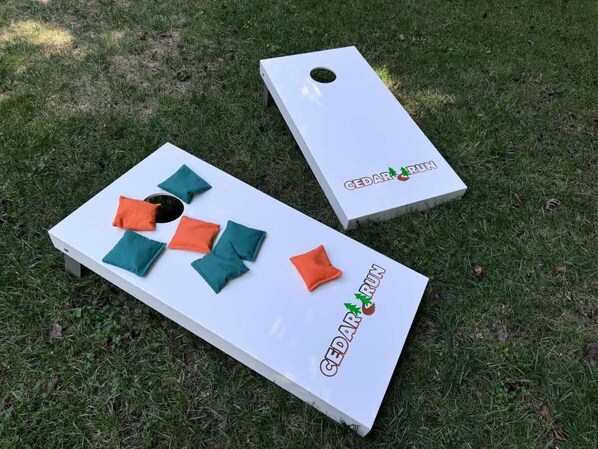 Two white wooden boards with 'CEDAR RUN' text and a hole in the center, placed on grass.