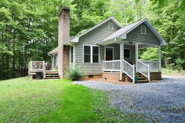 Une cabane avec une véranda, une cheminée et une terrasse.