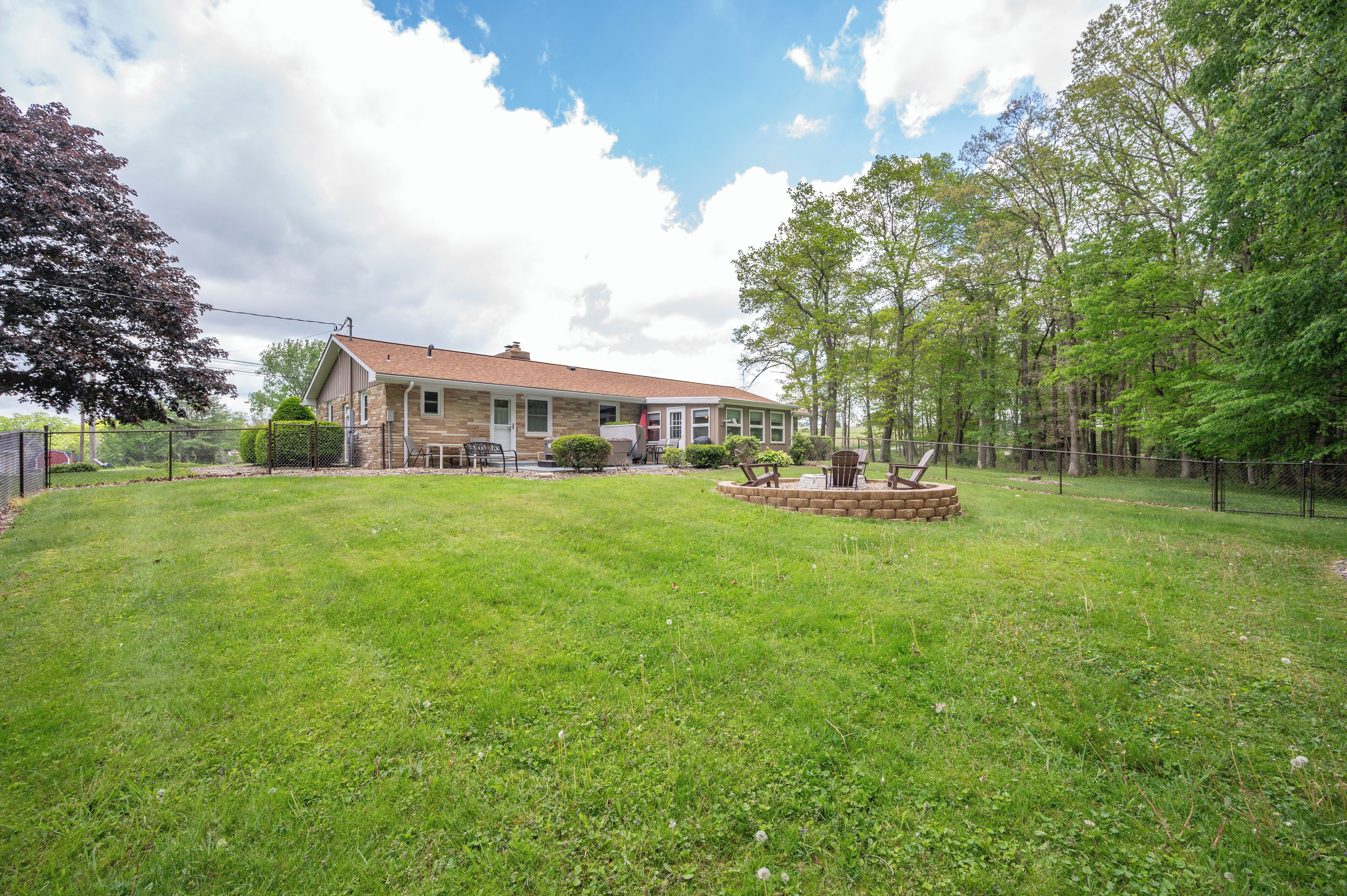 A house with a well-maintained lawn, a brick patio, and a wooden deck.