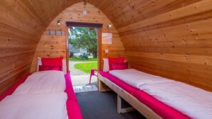 A cozy, wooden-paneled room with two single beds, each with a red pillow and white bedding. - Podumna Village  (Portumna)